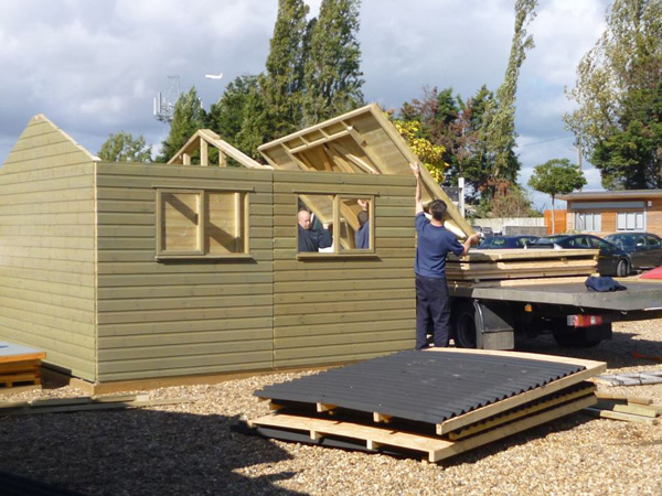 Shed installers dismantling an ex display timber workshop on to a lorry for delivery to its new garden A timber workshop is dismantled ready for installation in a new garden